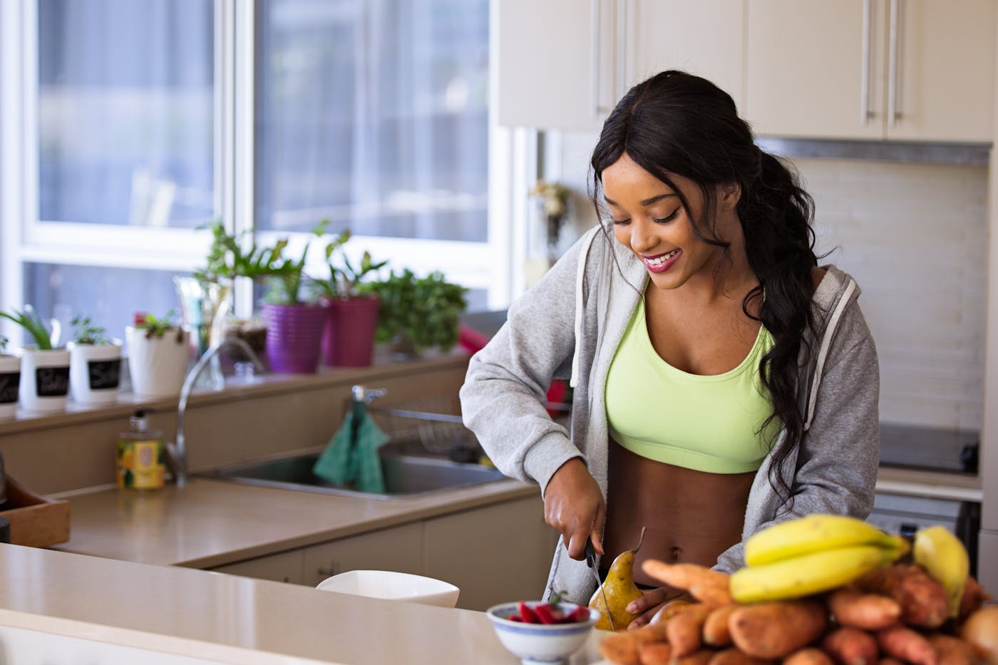 High-achieving woman smiling while prepping healthy whole foods in bright kitchen – Clean Eating Reset lifestyle